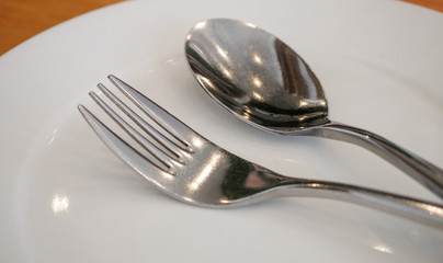 Close up fork and spoon in white plate 