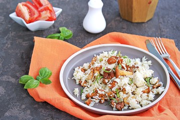 Pilaf with chanterelles and chicken on brown clay plate. Cooking wild mushrooms. Mushroom season recipes.