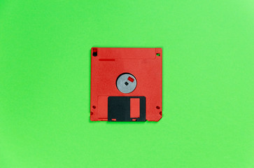 red floppy disk on green background. retro magnetic storage