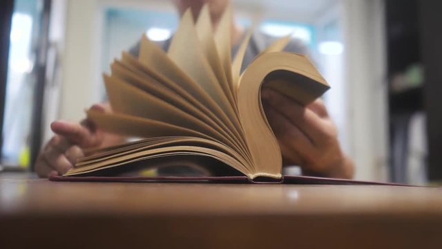 man is reading a book slow motion video. education learning library concept. man opens the book. man lifestyle turns the pages of the book