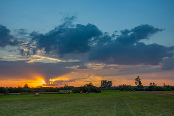 Colorful clouds during sunset and meadow