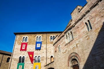The medieval Palazzo dei Consoli in the village of Bevagna. Brick and stone wall and mullioned windows. The Romanesque Church of San Silvestro. The banners of the districts. Perugia, Umbria, Italy.