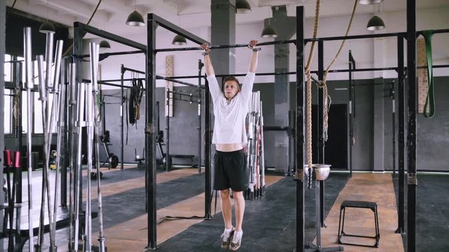 High pull-ups to chest to be fit. Best exercises in the gym. Strong middle-aged man pulls up on bar in gym and wears lift and grip gear. Strengthening muscles of back, body and chest