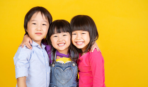 Portrait group of young happy little asian girls boy on yellow background with copy space. Education teampower brainstorm, childhood lifestyle back to school together concept