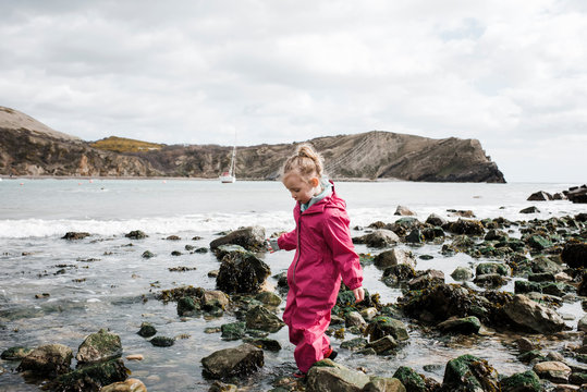 blonde girl walking on rocks at the beach at lulworth cove, England
