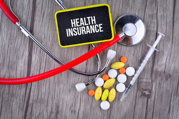 Pills, Syringe and Stethoscope with text Health Insurance