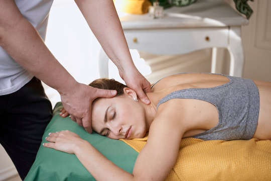 masseur works. man makes a beautiful woman massage