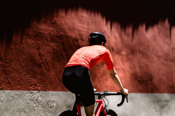 Rear view of cyclist riding bicycle against wall