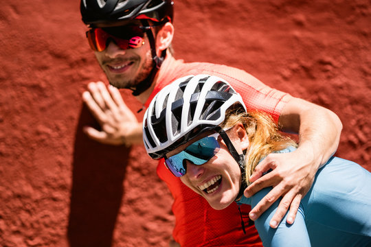 Portrait of female and male cyclists against red wall backdrop