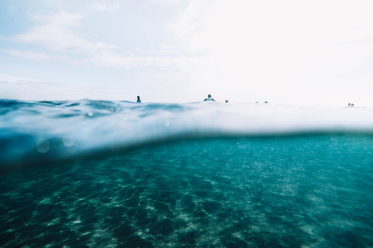 Pulled back over under of surfers waiting sitting on surfboard
