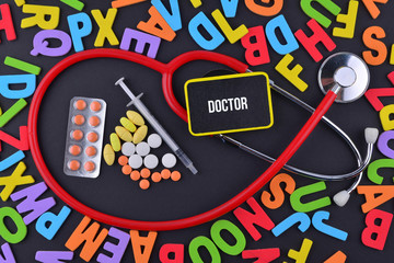 Pills, Syringe and Stethoscope with alphabet and text Doctor
