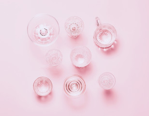 Many empty glasses on pink background. Top view, flat lay.