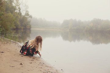 Blond girl dipping finger in lake