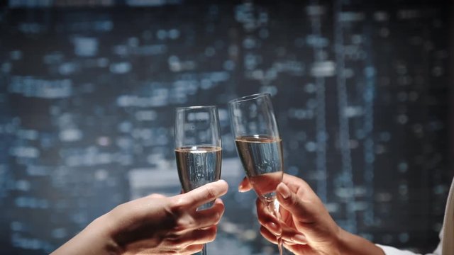 Close up of two hands with bocals of champagne making cheers and then drinking. Celebration of business success.
