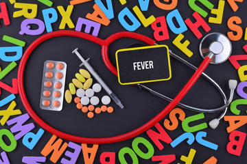 Pills, Syringe and Stethoscope with alphabet and text Fever