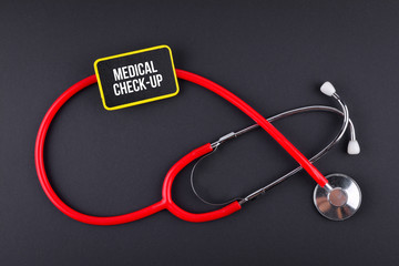 Stethoscope on black background with text. MEDICAL CONCEPT