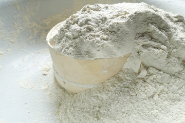  a sieve with white flour are in a large bowl. culinary light background