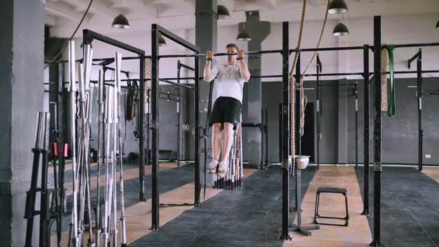 Reverse pull-ups to be fit. Best exercises in the gym. Strong middle-aged man pulls up on bar in gym and wears lift and grip gear. Strengthening muscles of back, wrist and chest.