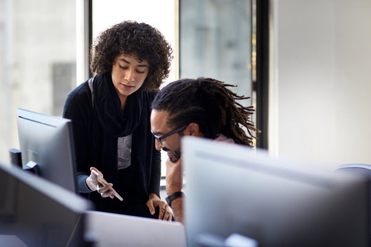 High angle view of businesswoman showing mobile phone to male colleague in office