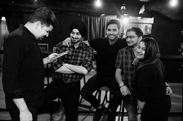 Group of indian friends sitting at lounge bar, having rest and look at menu.