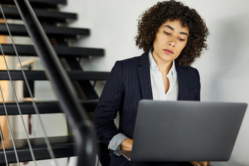 Businesswoman using laptop on steps