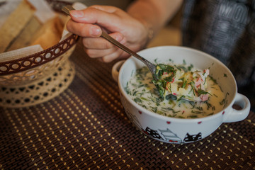 Cold soup name - okroshka, the national dish of the cuisine of Russia and Ukraine. Cold soup with fresh cucumbers, radishes, potato and sausage with yoghurt in bowl.