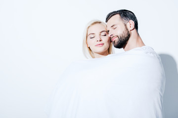 girlfriend and boyfriend covered in blanket with closed eyes on white
