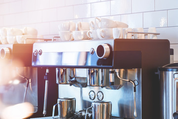 Professional coffee machine in a coffee shop with white cups stacked on top and light flare. Cafe...