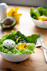 Salad with green lettuce, avocado, petals, egg and seeds. Healthy eating concept.
