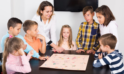 Children sitting at table with board game and dice