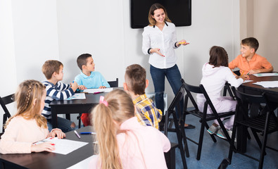 Fototapeta premium Little children with cheerful teacher drawing in classroom