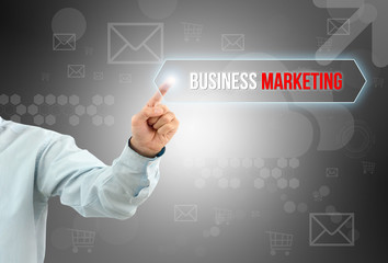 Obraz premium business man touch a button on an imaginary screen with text BUSINESS MARKETING