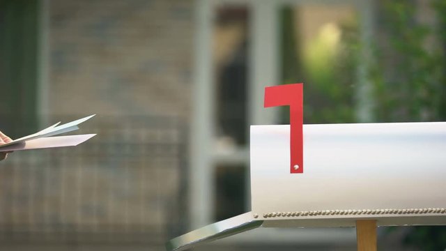 Home owner taking bills and letters from mailbox near house, postal service