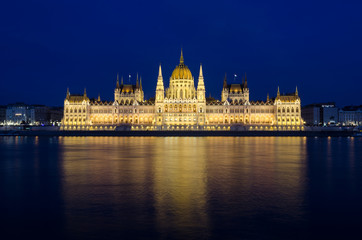 Illuminated Budapest hungarian Parliament at night reflected in the Danube river.