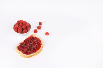 Red raspberries in a cup and toast with jam and fresh raspberries on a white isolated background, selective focus, copy space .