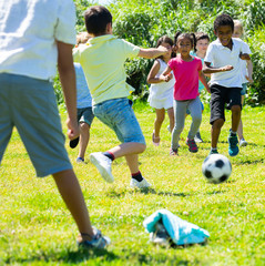 Obraz premium Happy kids are jogning and playing football in the park