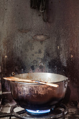 FIREPLACE WITH ANCIENT METAL PAN ON THE FIRE AND WOODEN SPOON. RURAL KITCHEN