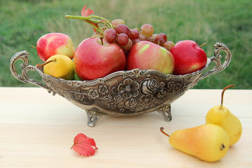 apples, grape and pears in a bowl on a wooden table