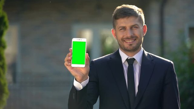Estate agent holding smartphone with green screen, app for housing rental