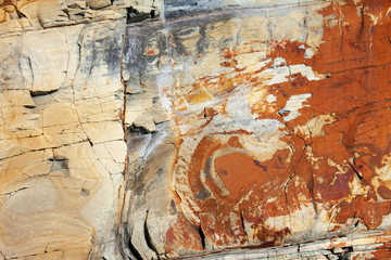 Stone texture in the light of the sun i n the summer. Cracks in natural stone. Different colors and a unique pattern on a stone a sunny day.