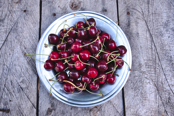 Cherries, top view of harvested red ripe cherries on wooden table and in plate