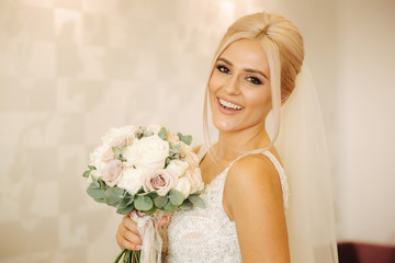 Portrait of gorgeous bride at home. Charming woman with bouquet. Morning of beautiful bride. Wedding day