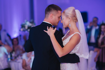 Portrait of first dance of stylish wedding couple. Handsome groom and elegant bride in the restaurant