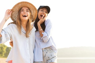 Two beautiful young women strolling on a beach. Female friends walking on the beach and laughing on...