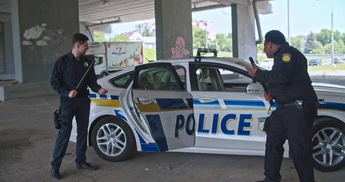 Nice mood cheerful cops let out black man offender dance together with funny cool moves in front of the police patrol car.
