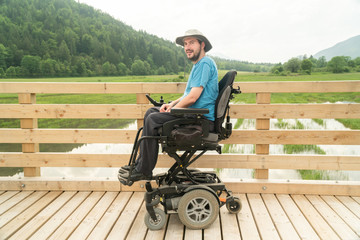 disabled happy young man in electric wheelchair on a boardwalk enjoying his freedom and smiling