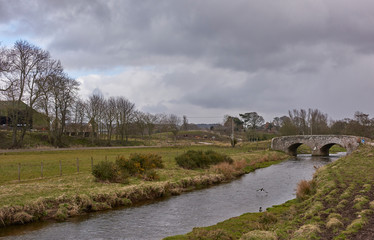 Fototapeta na wymiar The Stone road Bridge and Hamlet of Kinnell near Arbroath in Angus, on one overcast Spring day, with rain threatening.