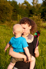 Mom and son having fun in nature in summer, mother holding her child with pinwheel