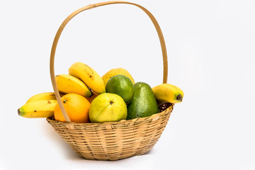 Avocado, papaya, orange, banana, guava and lemon in a basket made of bamboo, on a white background.