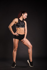 Fototapeta na wymiar Attractive young woman in sportswear posing on black background